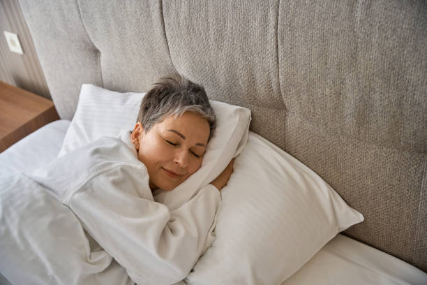 Adult lady in bathrobe resting in hotel room while sleeping stock photo