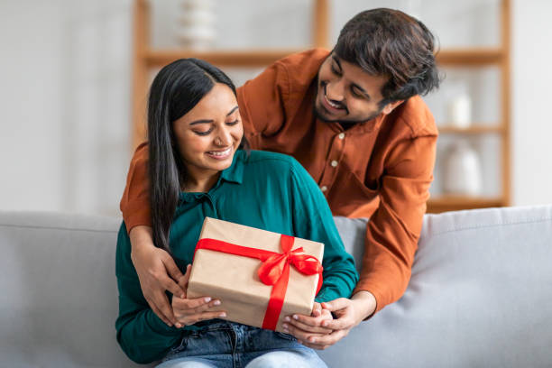istock Man Giving Gift to Woman on Couch 2164487154