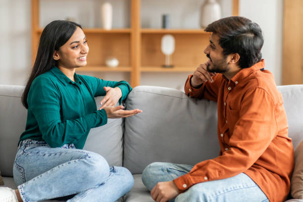 istock Cheerful Man and Woman Sit on Couch Talking 2164487255