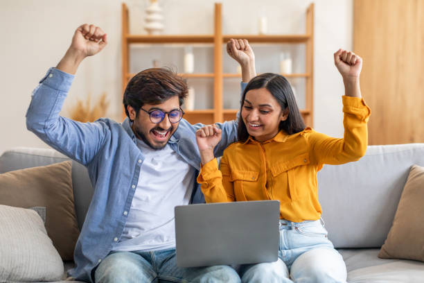 istock Man and Woman Sitting on a Couch With Laptop, Gesturing 2164487276