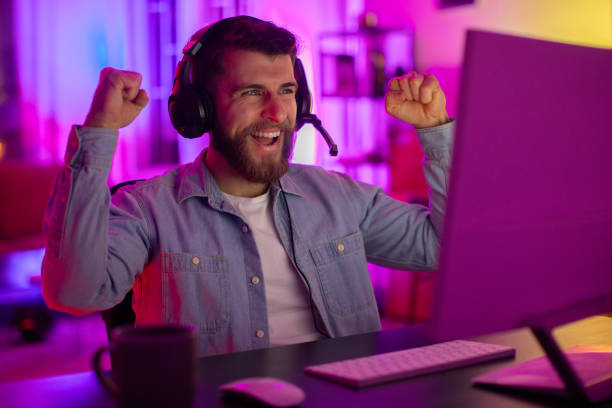 istock Excited gamer celebrates victory at PC in neon light 2164489311