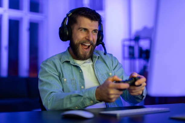 istock Gamer playing with controller and headphones at home 2164489415