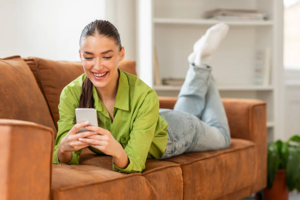 istock Woman Laying on a Couch Using a Cell Phone 2164491454
