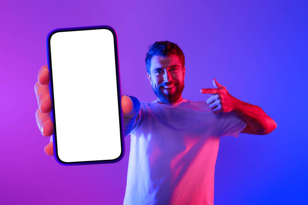istock guy pointing at large phone screen in neon lit studio 2164492180