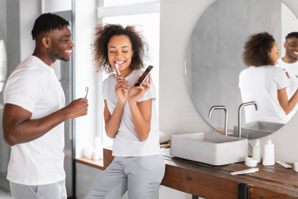 istock black couple brushing teeth using mobile phone in modern bathroom 2164492299
