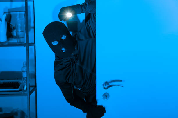 istock Burglar with flashlight opening a door stealthily 2164493490