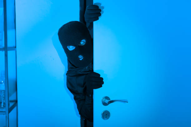 istock Sneaky burglar man opening a door cautiously 2164493491