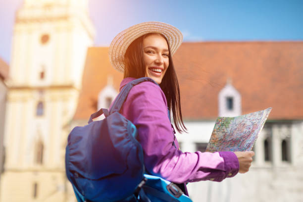 istock Smiling woman tourist looking back with map 2164495962