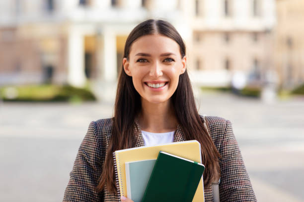 istock Smiling young woman student with notebooks in city 2164496006