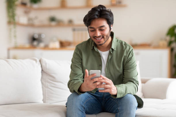 istock Man Sitting on Couch Looking at Phone 2164497659