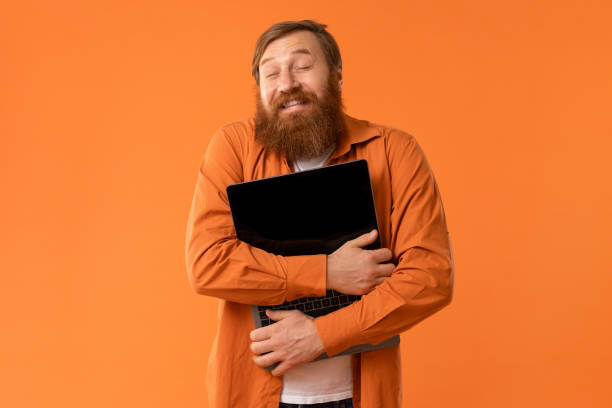 istock Happy Redhaired Bearded Man Hugging His Laptop Computer, Orange Studio 2164497858