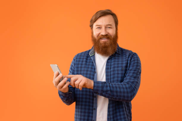 istock Cheerful middle aged man with red hair touching phone, studio 2164497867