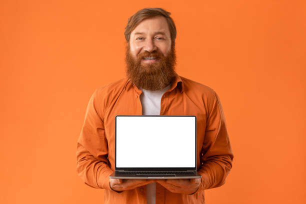 Smiling Redhaired Bearded Man Holding Laptop With Blank Screen, Studio