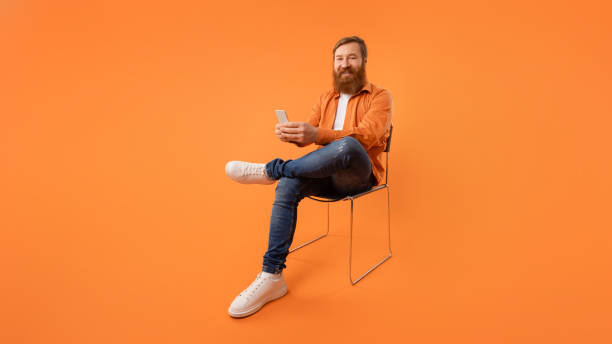 istock Man with red beard uses mobile phone sitting, studio shot 2164497979