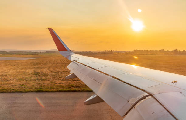View on sunset and airplane wing from the inside. Airplane window view.