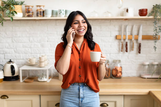 istock Woman chatting on phone with coffee in kitchen 2164499398