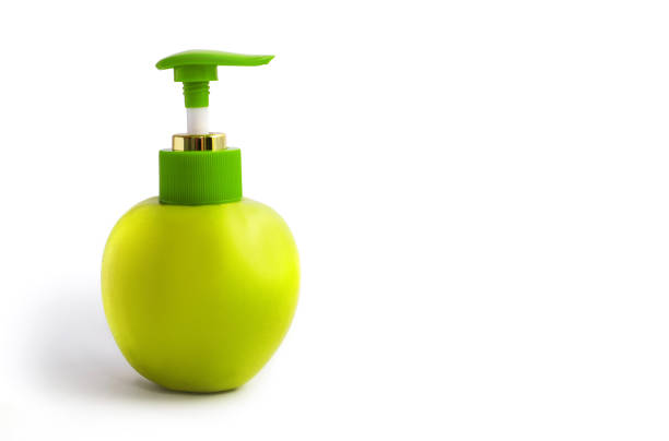 Green fresh apple with a dispenser on a white isolated background. Fresh apple with dispenser and free space for text. The concept of natural cosmetics or skin care soaps