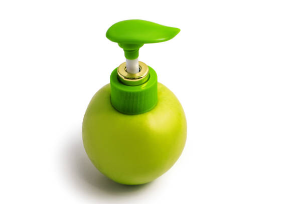 Apple with a dispenser on a white background. Green juicy apple with a plastic dispenser on an isolated white background. The concept of natural cosmetic creams or soaps for the skin