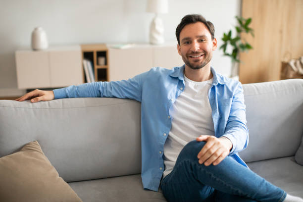 istock Man Sitting on Couch in a Living Room 2164502179