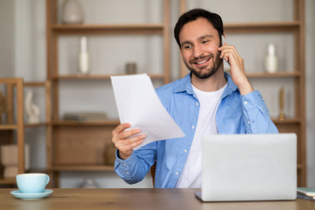 istock Man Talking on Phone Holding Piece of Paper 2164502190