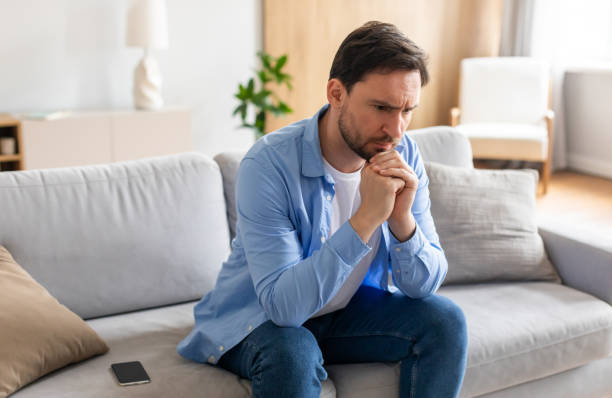 istock Man Sitting on Couch With Hand on Chin 2164502219