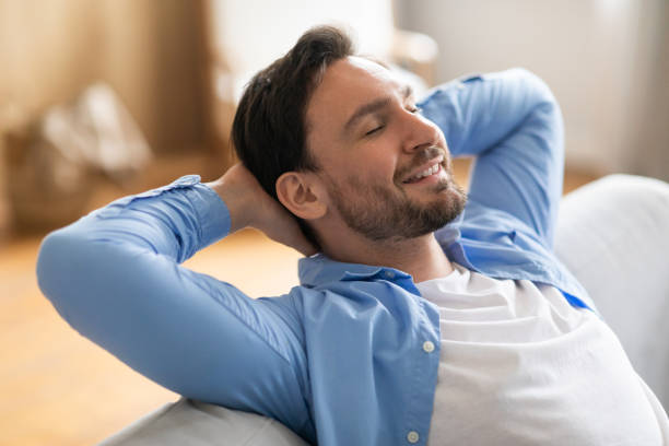 istock Man Relaxing on Couch With Hands on Head 2164502243