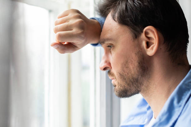 istock Pensive Man Gazing Out of a Window During Daylight Hours 2164502256