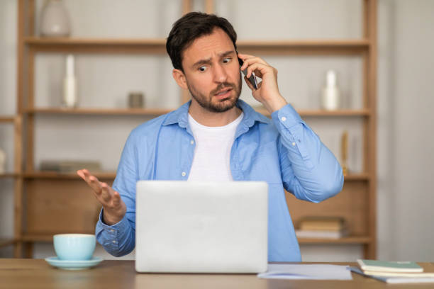 istock Concerned Man Talking On The Phone While Working At Home 2164502287