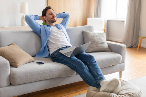 istock Man Relaxing on Couch With Laptop, Home Interior 2164502328