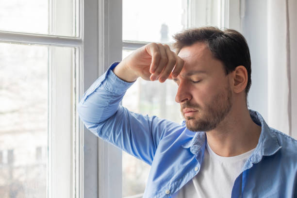 Man Holding Head in Front of Window, Closeup