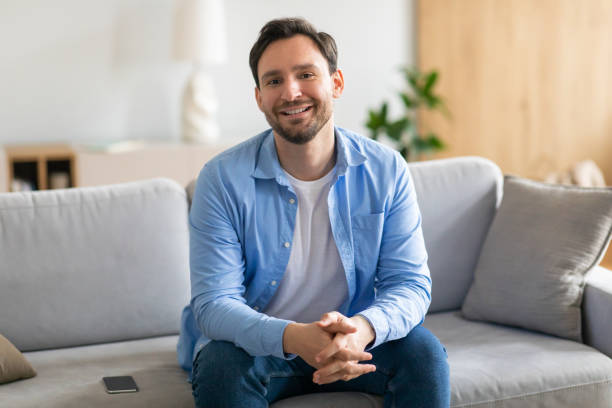 istock Man Sitting on Couch in Living Room 2164502353