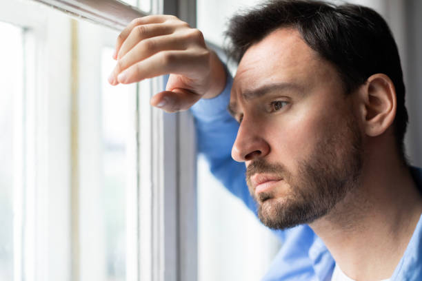 istock Sad Man Looking Out of a Window 2164502388