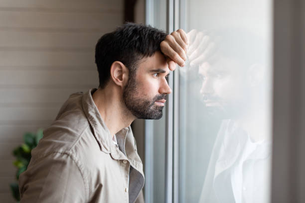 istock Man Gazing Out Window With Hand on Head 2164504665