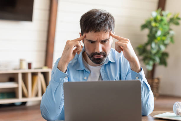 istock Man Concentrating Intensely While Working on Laptop in Home Office 2164504774