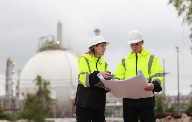 istock Male and  Female engineers stand Discussing the building plan at the site, Engineers working outdoors and use walkie-talkies against the spherical  gas storage tank in the background 2164505395