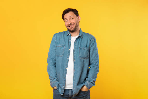istock Man Standing in Front of Yellow Background, Hands in Pockets 2164506564