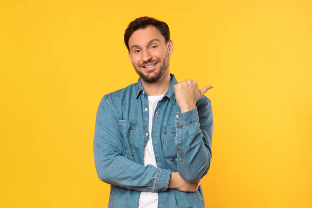 istock Man in Blue Shirt Pointing at Something With Thumb 2164506568
