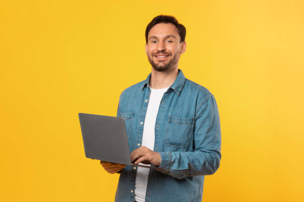 istock Man in Blue Shirt Holding Laptop on Yellow 2164506570