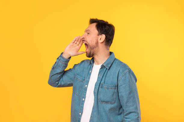 istock Man Standing in Front of Yellow Wall With Mouth Open 2164506583