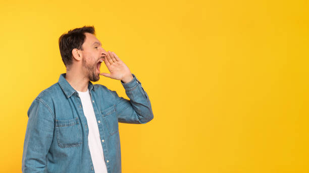 istock Man Standing in Front of Yellow Wall and Screaming 2164506597