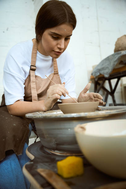 istock Potter maker in apron working with clay on pottery wheel in workshop 2164507966