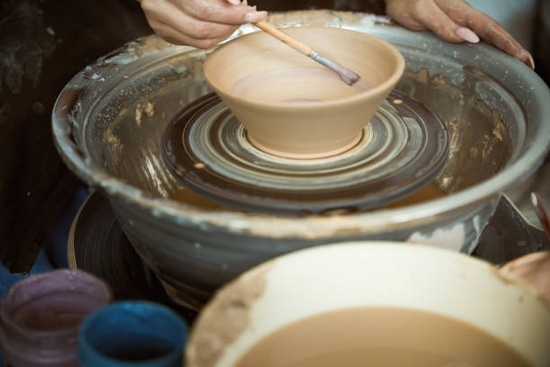 Close up of hands of female potter, creating an earthen bowl on the circle. Handicraft ceramic pottery production