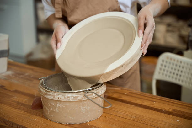 istock Close up of female ceramist making a clay plate while using special mold 2164508646