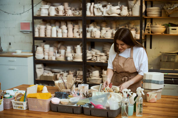 istock Young woman in apron showing process of creating pottery 2164508661
