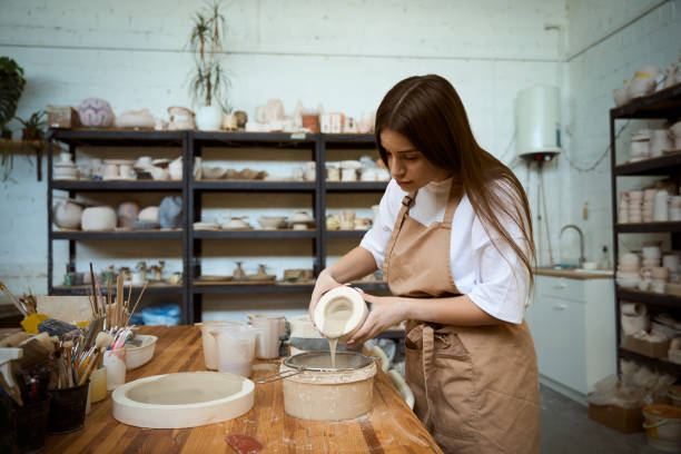 istock Ceramic artist putting finish ceramic glaze on a crafted cup in her studio workshop 2164508667