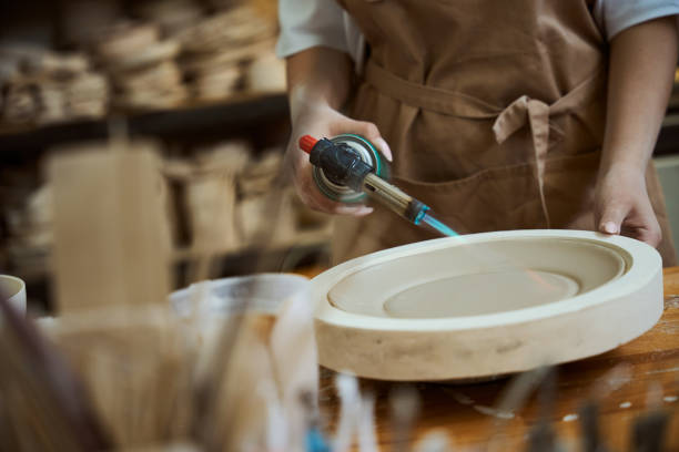 istock Woman in an apron drying earthenware plate using dryer tool 2164508691