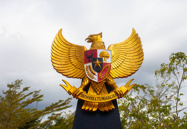 garuda pancasila emas, lambang nasional indonesia dengan latar belakang langit biru dan berawan. - monumen pancasila potret stok, foto, & gambar bebas royalti