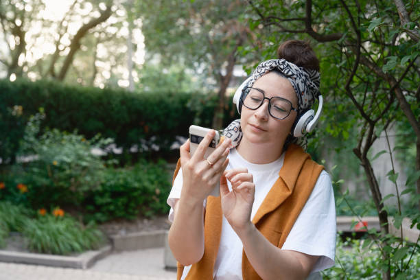 A woman is looking at her phone while wearing headphones