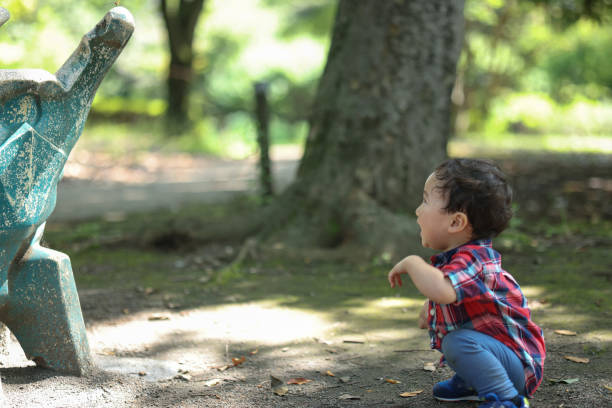 Curious toddler gently touches a small duckling held by their grandparent, fostering a connection with nature and animals