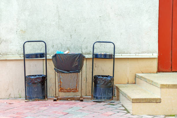 Three metal garbage cans stand in a row near the wall